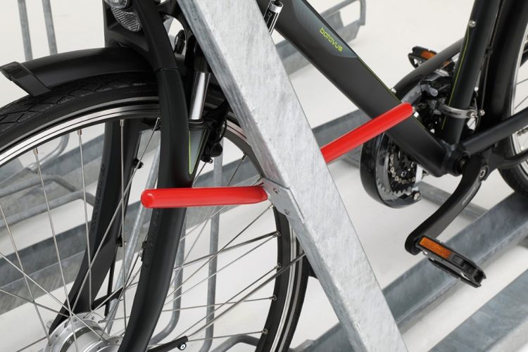 Close-up of a bike parked in the Optima Two Tier Rack with red bar attached to the steel rack