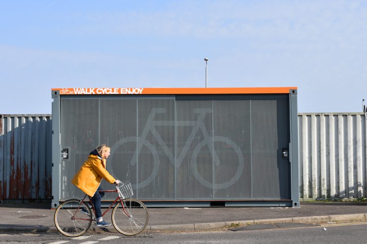 Closed view of the Cyclehoop Container Cycle Hub on a street with a cyclist travelling on the road