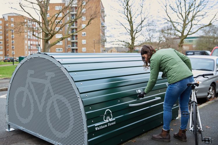 Cyclist locking the Cyclehoop Bike Hangar with a key while holding onto their bicycle