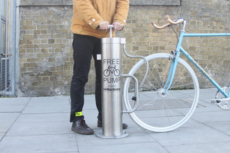 Public bike pump, which is clearly labelled, being used by a cyclist to inflate a tyre