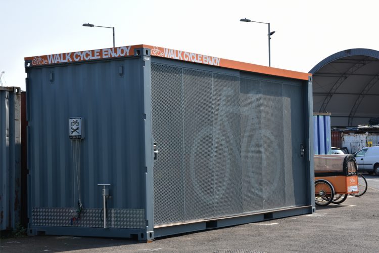 Container Cycle Hub located in an urban development, the gate is closed, and the hub has clear bike parking signs
